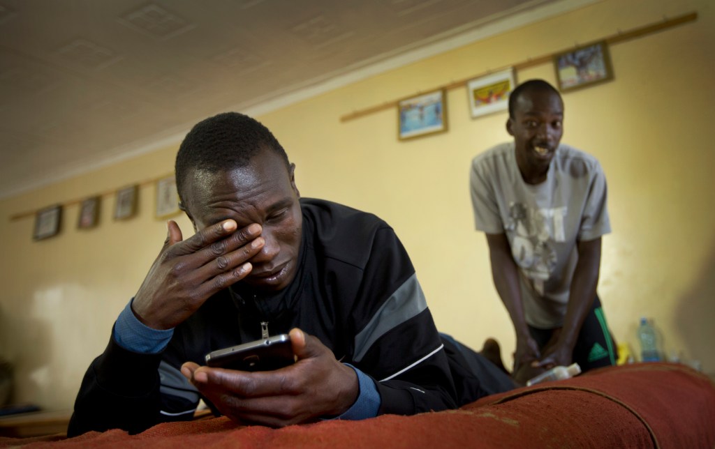 In this Jan. 30, 2016, photo Kenyan long-distance runner Geoffrey Kipsang Kamworor checks messages on his phone as he receives an after-training massage at the Global Sports camp near the village of Kaptagat in western Kenya. At the high-altitude training camp in Kenya, star athletes turn their back on modernity and bling for a simple life of hard training and communal, egalitarian living. (AP Photo/Ben Curtis)