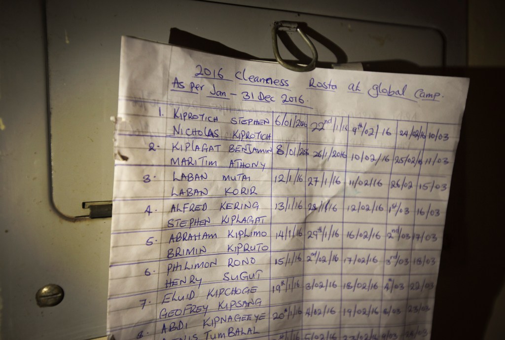In this Jan. 30, 2016, photo a hand-written roster pinned to the wall tells runners when its their turn to do communal chores, at the Global Sports camp near the village of Kaptagat in western Kenya. At the high-altitude training camp in Kenya, star athletes turn their back on modernity and bling for a simple life of hard training and communal, egalitarian living. (AP Photo/Ben Curtis)