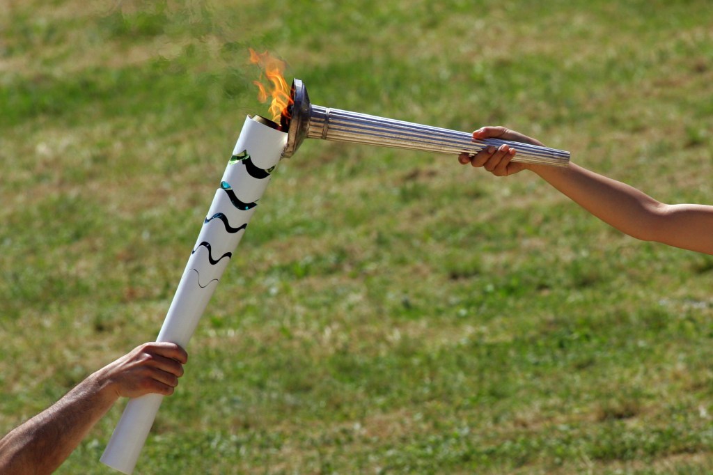 OLYMPIA, GREECE - APRIL 20: Actress Katerina Lechou (R) acting the high pristess passes the flame from the Olympic Torch at the Ancient Stadium during the Rehearsal for the Lighting Ceremony of the Olympic Flame at Ancient Olympia on April 20, 2016 in Olympia, Greece. (Photo by Milos Bicanski/Getty Images)