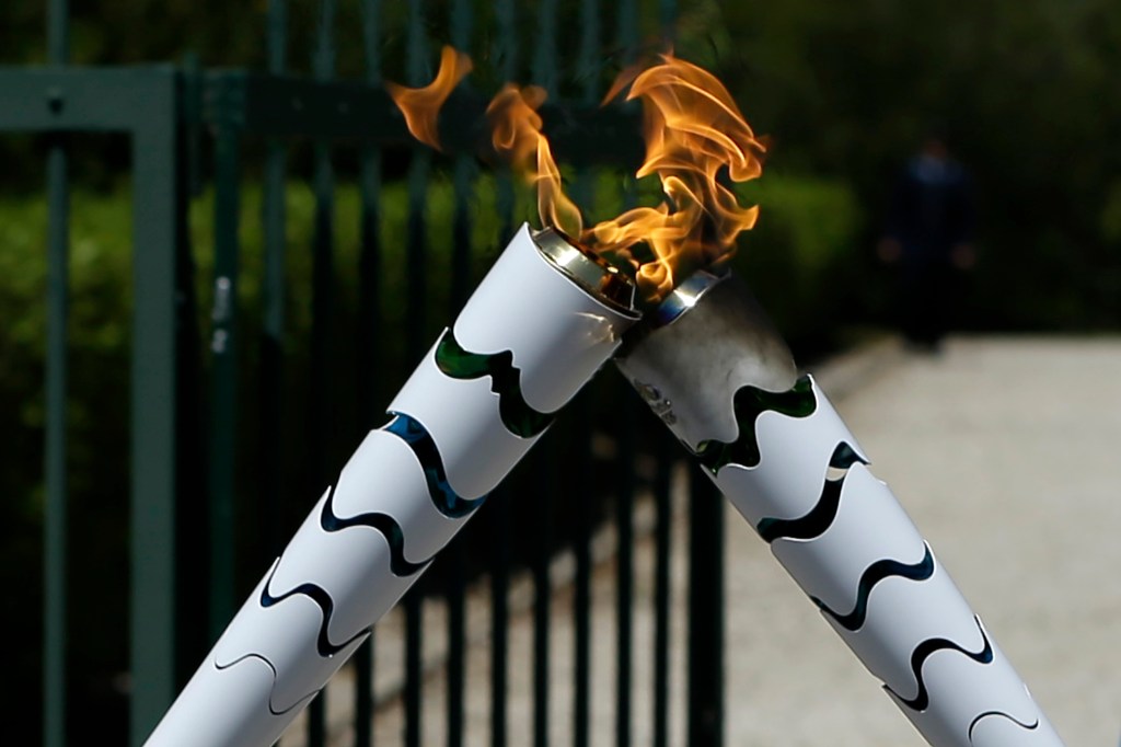 The Olympic flame is symbolically passed from one torch to another after after the official ceremonial lighting of the flame in Ancient Olympia, Greece, on Thursday, April 21, 2016, with the former Brazilian volleyball player Giovane Gavio, left, and Greek gymnast Eleftherios Petrounias, right. The flame will be transported by torch relay to the Brazilian city of Rio de Janeiro, which will host the 2016 Olympic Games. (AP Photo/Thanassis Stavrakis)
