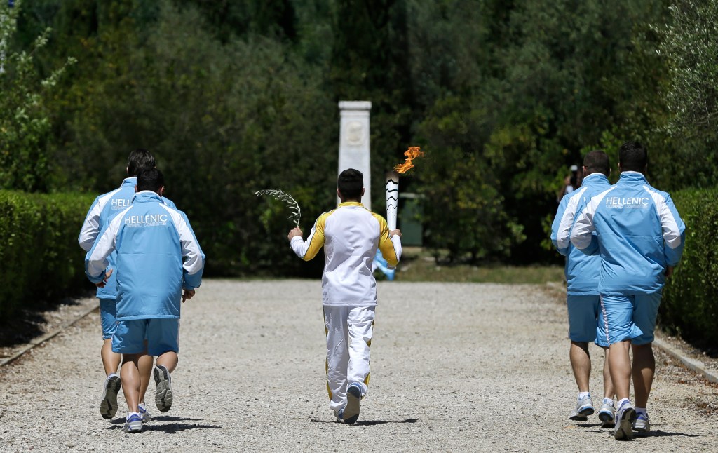 Greek gymnast Eleftherios Petrounias carries a torch with the Olympic flame during the ceremonial lighting of the Olympic flame in Ancient Olympia, Greece, Thursday, April 21, 2016. The flame will be transported by torch relay to the Brazilian city of Rio de Janeiro, which will host the 2016 Olympic Games. (AP Photo/Thanassis Stavrakis)