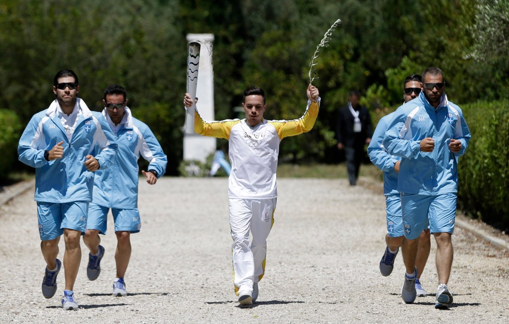 Greek gymnast Eleftherios Petrounias carries a torch with the Olympic flame during the ceremonial lighting of the Olympic flame in Ancient Olympia, Greece, Thursday, April 21, 2016. The flame will be transported by torch relay to the Brazilian city of Rio de Janeiro, which will host the 2016 Olympic Games. (AP Photo/Thanassis Stavrakis)