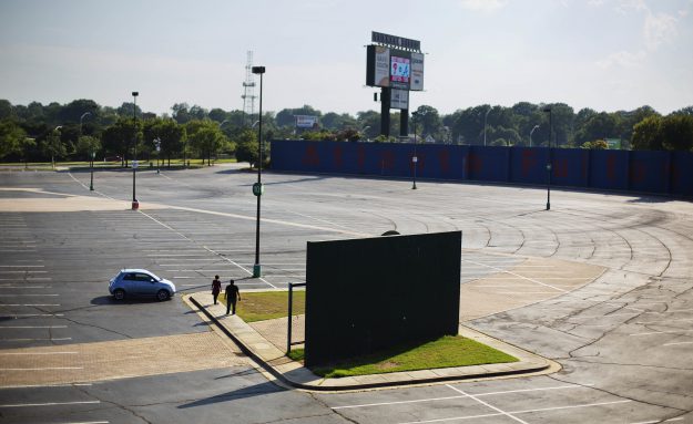 In this Wednesday, July 20, 2016 photo, visitors stand next a piece of the outfield wall of what used to be Atlanta-Fulton County Stadium, home of the 1996 Summer Olympic Games baseball event, and former home of the Atlanta Braves baseball team in Atlanta. The stadium served out the 1996 baseball season, then was imploded the following summer to make way for a parking lot serving adjacent Turner Field. (AP Photo/David Goldman)