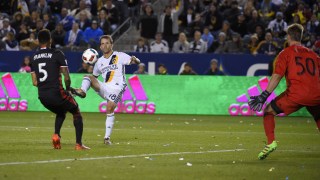 Los Angeles Galaxy forward Mike Magee, center, kicks the ball past D.C. United goalkeeper Andrew Dykstra, right, for a goal as defender Sean Franklin defends during the second half of an Major League Soccer match, Sunday, March 6, 2016, in Carson, Calif. The Galaxy won 4-1. (AP Photo/Mark J. Terrill)