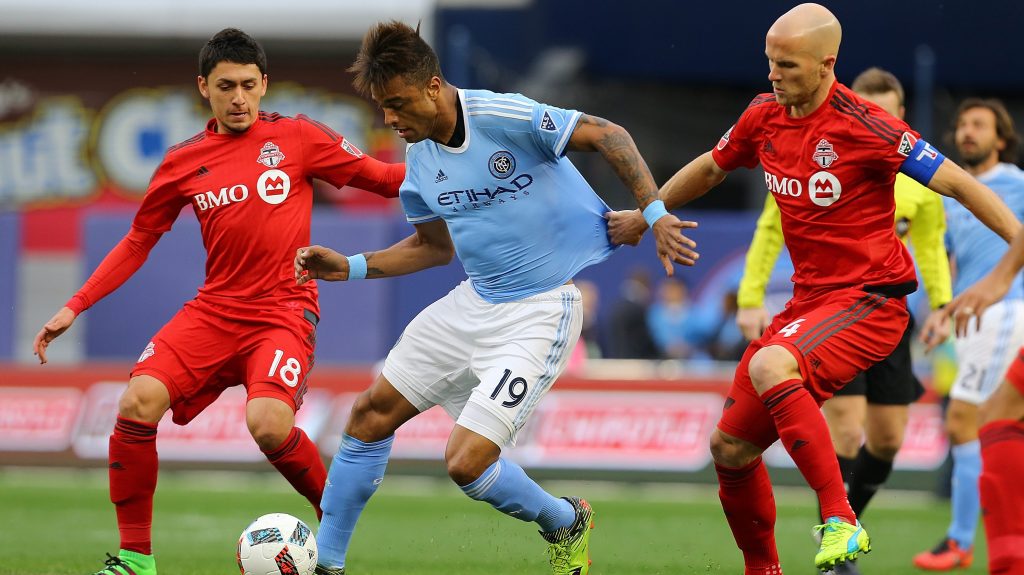 NEW YORK, NY - MARCH 13: Khiry Shelton #19 of New York City FC carries the ball against Marco Delgado #18 and Michael Bradley #4 of Toronto FC at Yankee Stadium on March 13, 2016 in the Bronx borough of New York City. (Photo by Mike Stobe/Getty Images)
