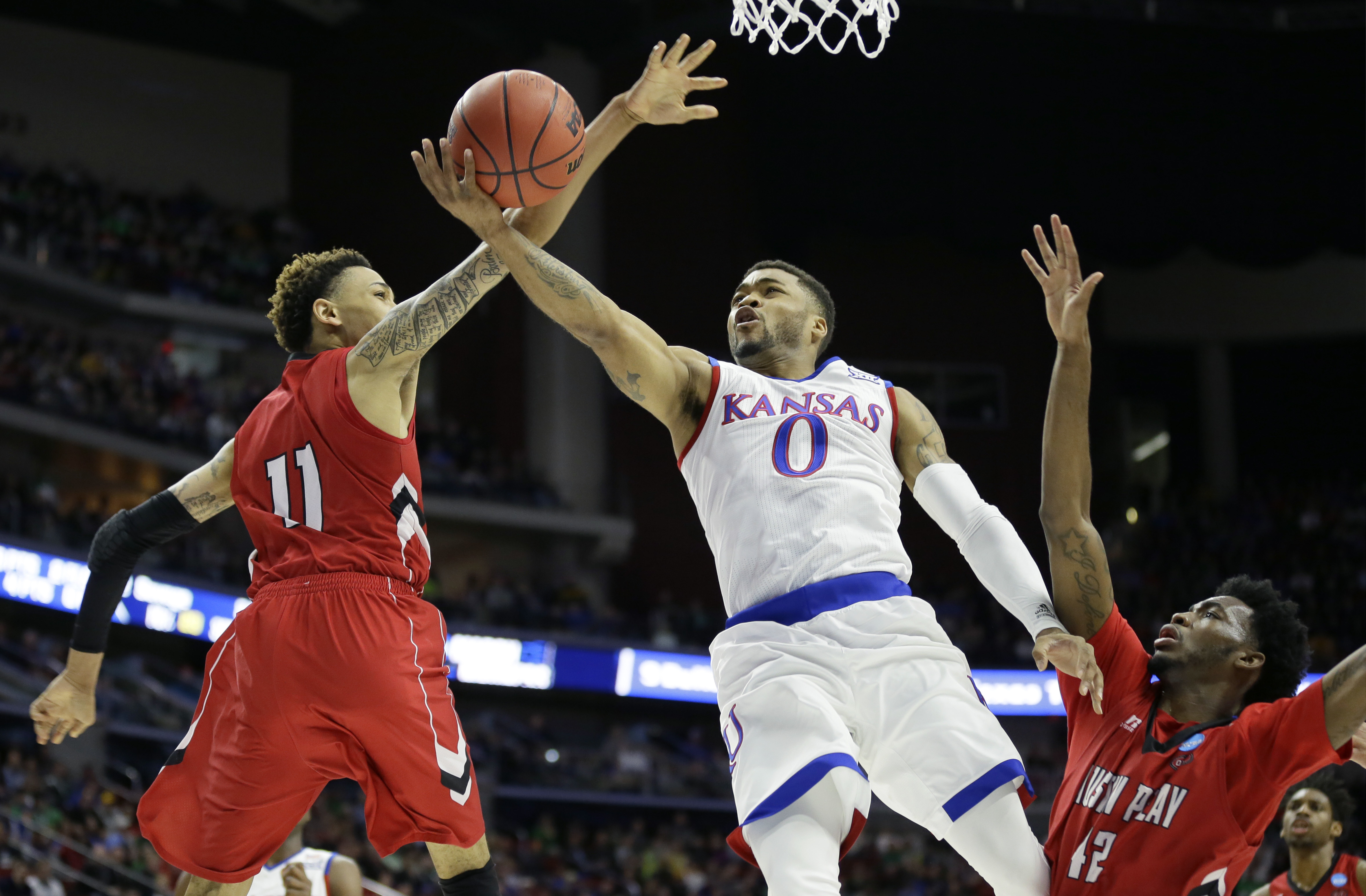 Kansas guard Frank Mason III, center, drives to the basket between Austin Peay defenders Khalil Davis, left, and Kenny Jones, right, during the first half of a first-round men's college basketball game in the NCAA Tournament, Thursday, March 17, 2016, in Des Moines, Iowa. (AP Photo/Charlie Neibergall)
