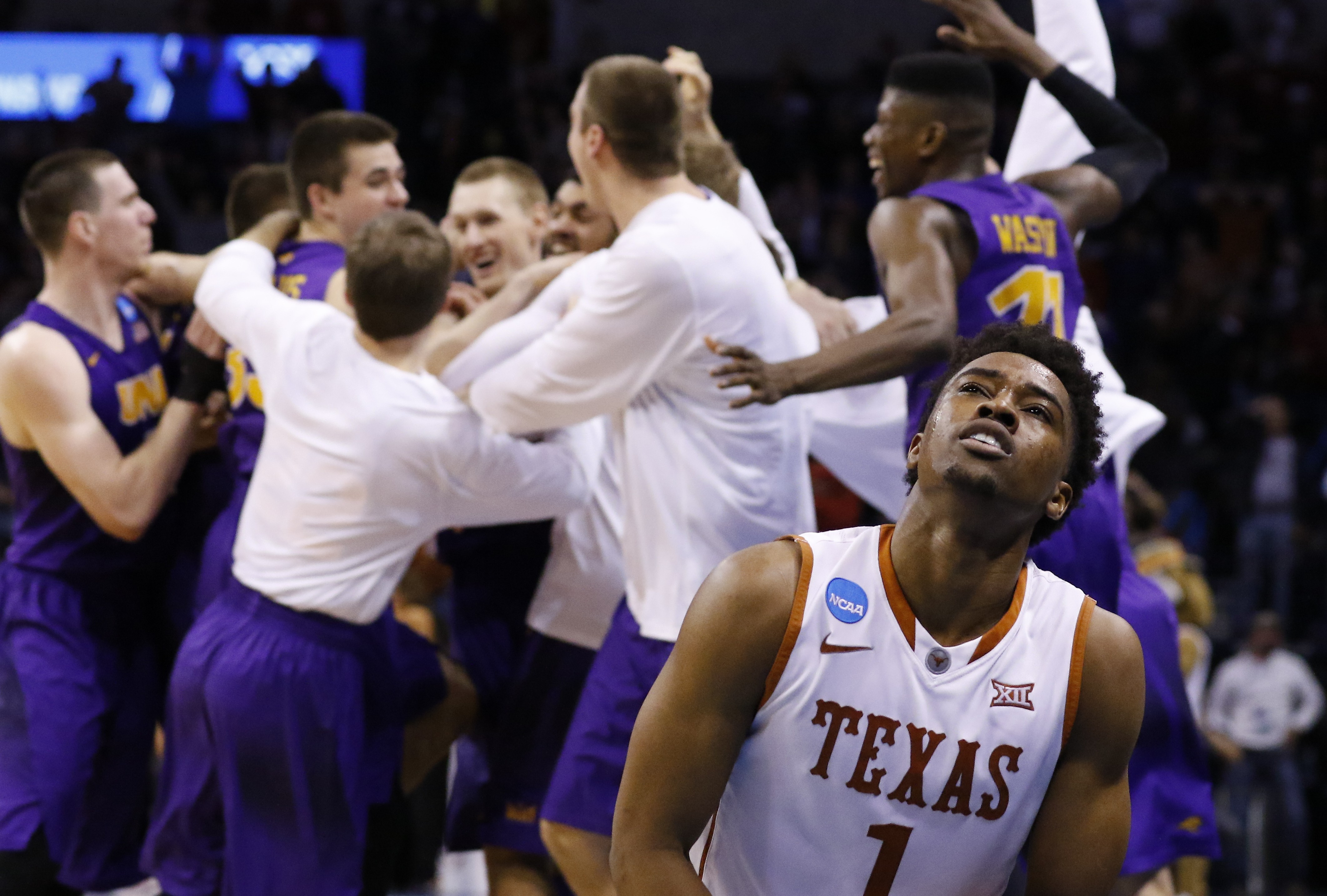 Texas guard Isaiah Taylor (1) reacts as the Northern Iowa team celebrates after guard Paul Jesperson made a last-second half-court shot to win the the first-round men's college basketball game in the NCAA Tournament in Oklahoma City, Friday, March 18, 2016. Northern Iowa won 75-72. (AP Photo/Alonzo Adams)
